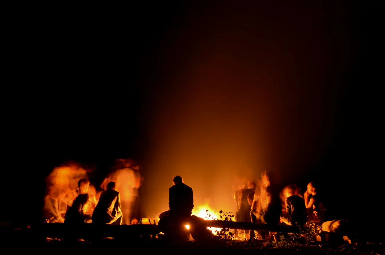 Young Rangers and leaders gathered around a glowing campfire at night